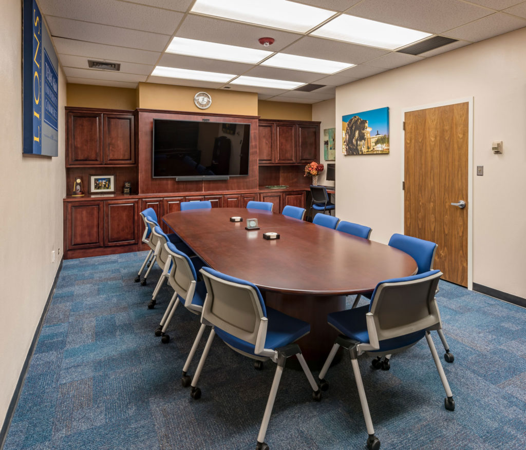 Completed Texas A&M University Commerce commercial renovation of a conference room with large table and 12 blue chairs